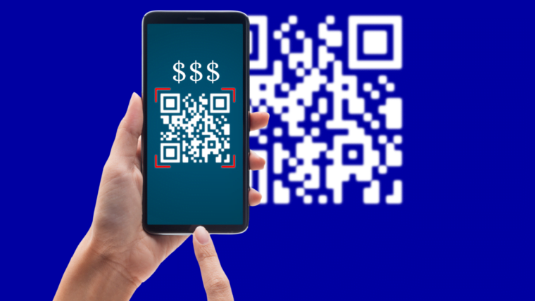 Na imagem, em um fundo azul com um QR Code branco desfocado, uma pessoa segura um smartphone que exibe três cifrões e o QR Code na tela. Com a outra mão, essa mesma pessoa simula o toque na tela.